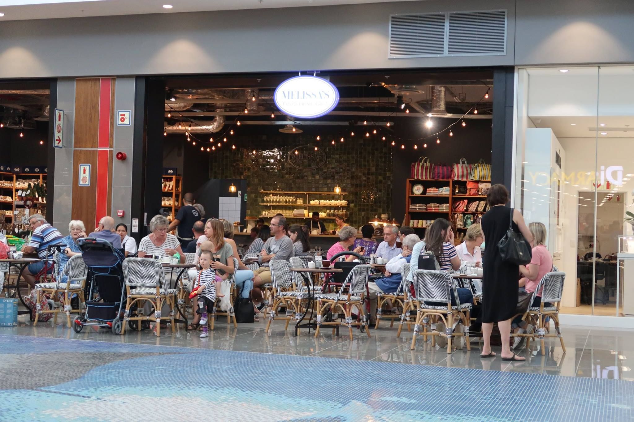 Visitors enjoy a bustling café within Whale Coast Mall, highlighting its role as a central shopping and dining destination. The modern decor and diverse clientele reflect the mall's accessibility and appeal to both locals and tourists along the Hermanus coastline.